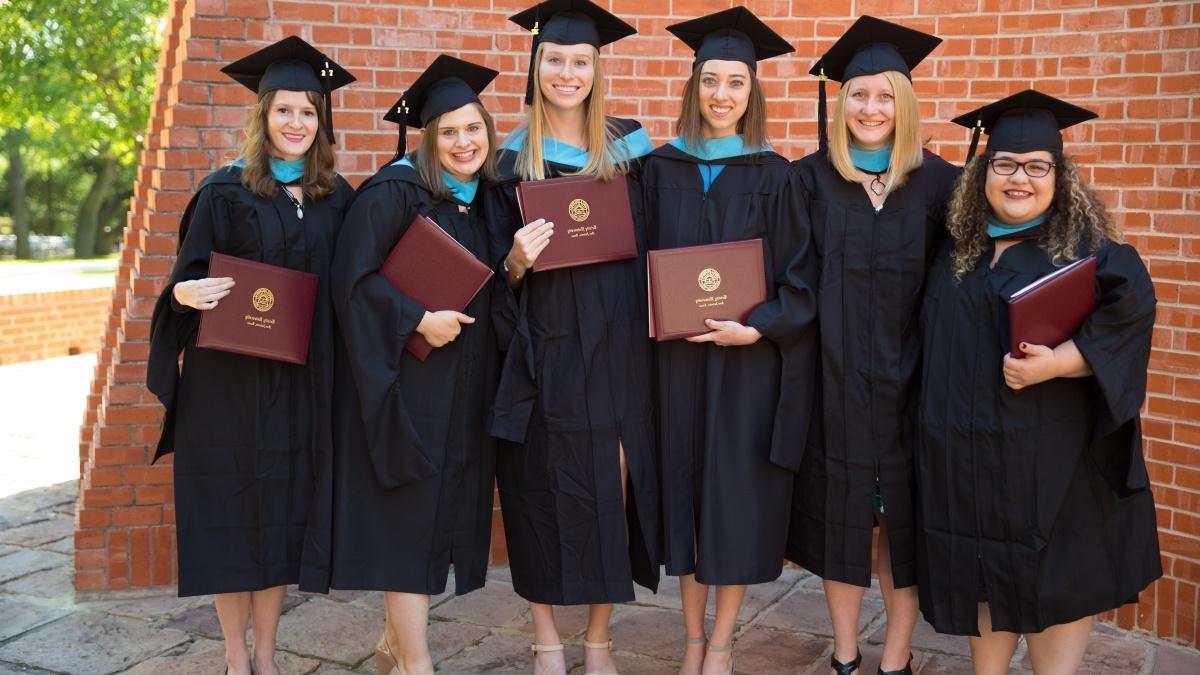 Graduation students in their caps and gowns holding their diplomas