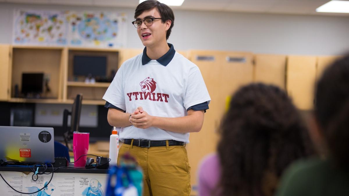 Student teacher in a Trinity shirt presenting to classroom